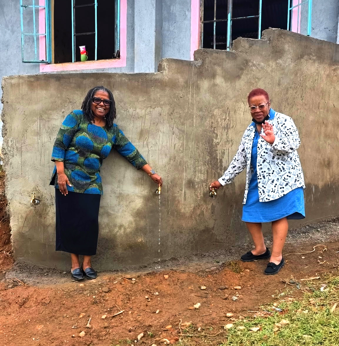 President of B&M Construction, Inc., Barbara Myrick and company in front of faucets sourced by the Joy's Well Clean Water Project in Kenya