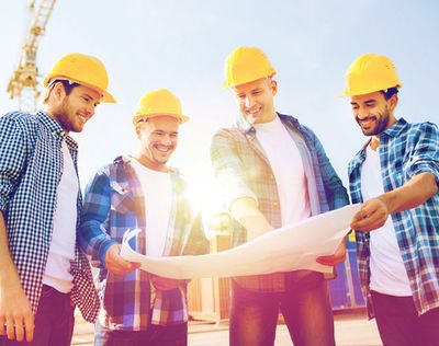 Smiling B&M construction team reviewing blueprints