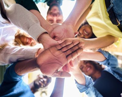 B&M community members circled up with their hands stacked on top of each other
